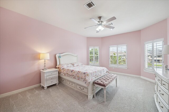 bedroom with baseboards, visible vents, and light carpet