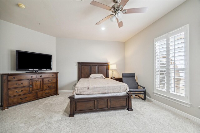 bedroom with light colored carpet, a ceiling fan, and baseboards