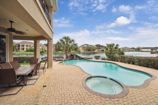 view of swimming pool featuring a water view, a pool with connected hot tub, and a patio area