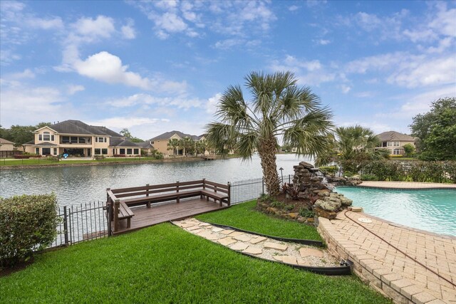exterior space with a lawn, a water view, fence, and a fenced in pool