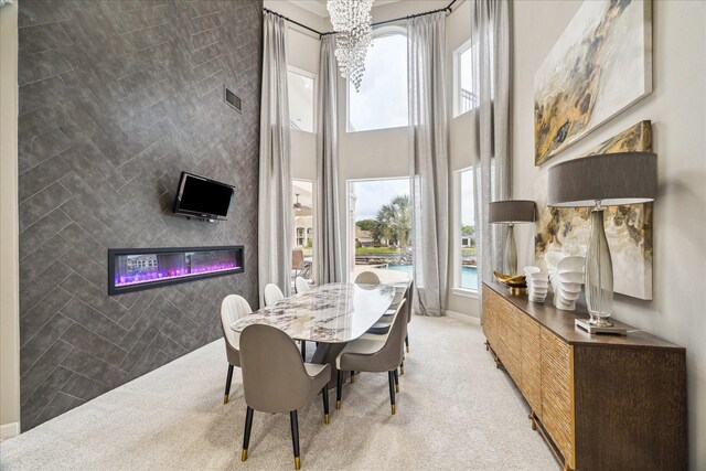 dining room featuring visible vents, a notable chandelier, a glass covered fireplace, and carpet