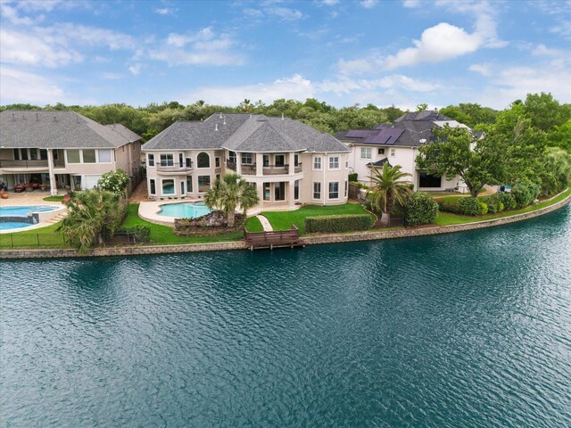 pool featuring a hot tub, a patio, a water view, and a yard