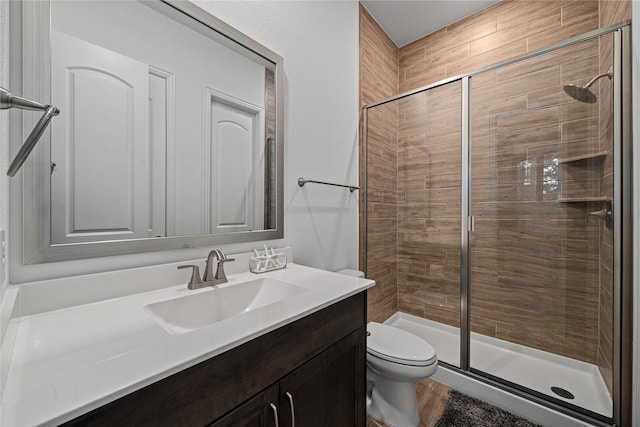 bathroom with toilet, a shower stall, and vanity