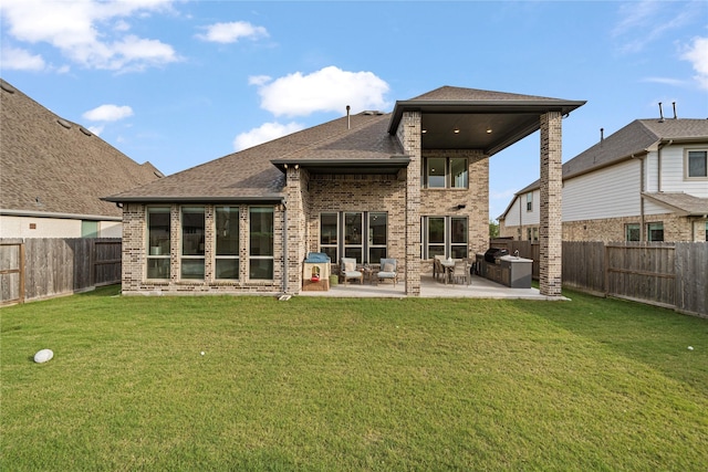 rear view of house with a lawn, brick siding, a patio, and a fenced backyard