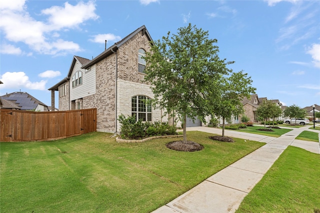view of property exterior featuring a lawn, fence, stone siding, and concrete driveway