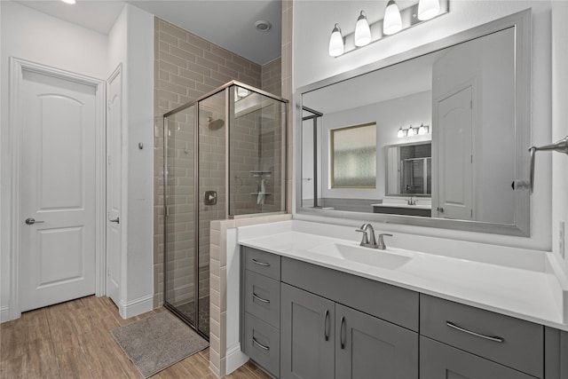bathroom featuring wood finished floors, a stall shower, and vanity