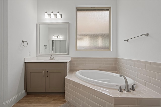 full bath with a garden tub, plenty of natural light, wood finished floors, and vanity