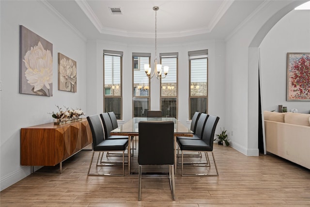 dining room featuring baseboards, arched walkways, wood finished floors, and a chandelier