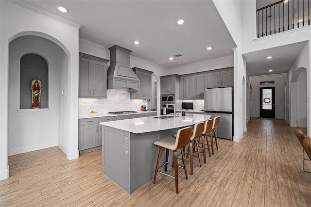 kitchen with a sink, appliances with stainless steel finishes, gray cabinets, and custom range hood