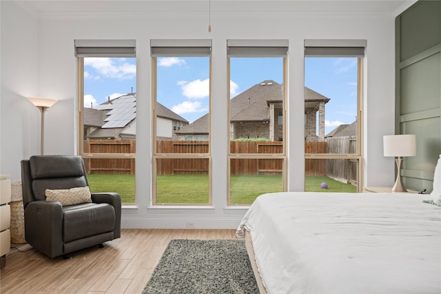 bedroom with crown molding, a residential view, and light wood-style flooring