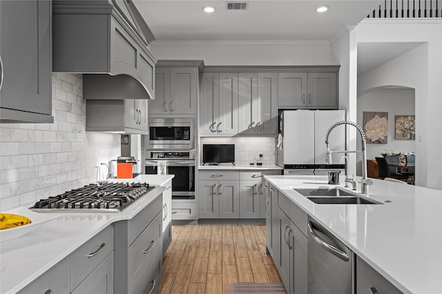 kitchen featuring a sink, appliances with stainless steel finishes, gray cabinetry, and ornamental molding