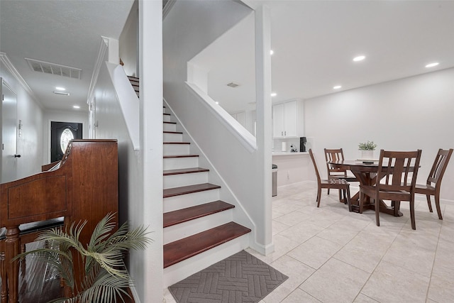 stairs with crown molding, recessed lighting, visible vents, and tile patterned flooring