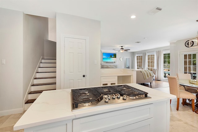14010 Lakewood Crossing Blvd, Houston, TX 77070 - kitchen featuring ceiling fan, a kitchen island, light stone counters, baseboards, and stainless steel gas stovetop