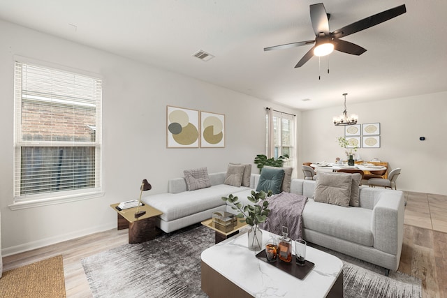 living area with visible vents, baseboards, ceiling fan with notable chandelier, and wood finished floors