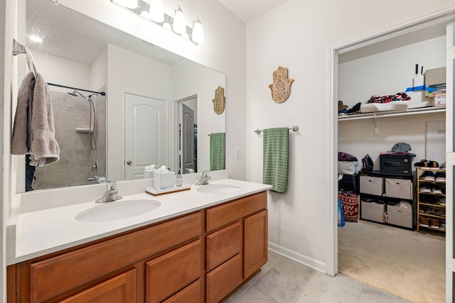 bathroom with baseboards, double vanity, a walk in closet, and a sink