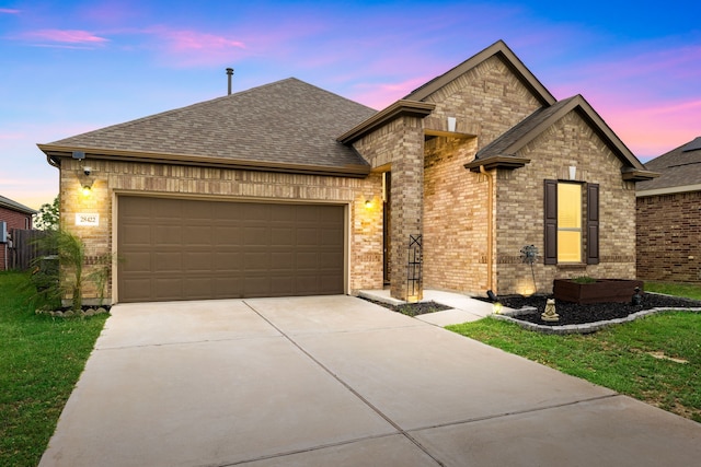 french country home with a shingled roof, brick siding, a garage, a front yard, and concrete driveway