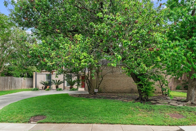 view of front of home with fence, driveway, a front lawn, and brick siding