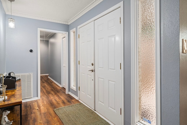 interior space featuring visible vents, ornamental molding, wood finished floors, baseboards, and a textured ceiling