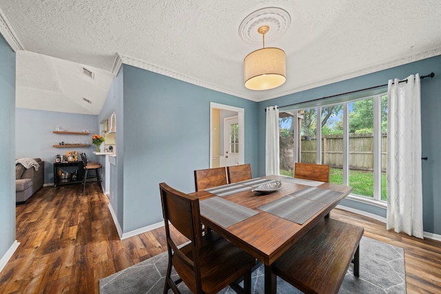 dining room featuring a textured ceiling, baseboards, wood finished floors, lofted ceiling, and visible vents