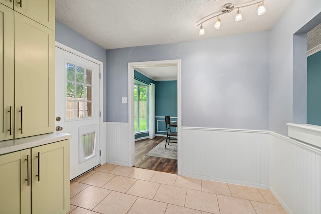 entryway featuring heating unit, a wainscoted wall, a textured ceiling, and light tile patterned flooring