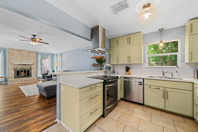 kitchen with appliances with stainless steel finishes, a sink, wall chimney exhaust hood, a peninsula, and visible vents