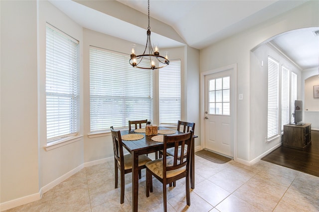 dining area featuring an inviting chandelier, arched walkways, light tile patterned floors, and lofted ceiling