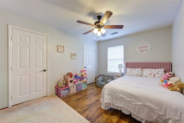 bedroom featuring ceiling fan, visible vents, and wood finished floors