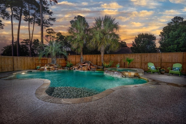pool at dusk with a patio, a fenced backyard, and a pool with connected hot tub