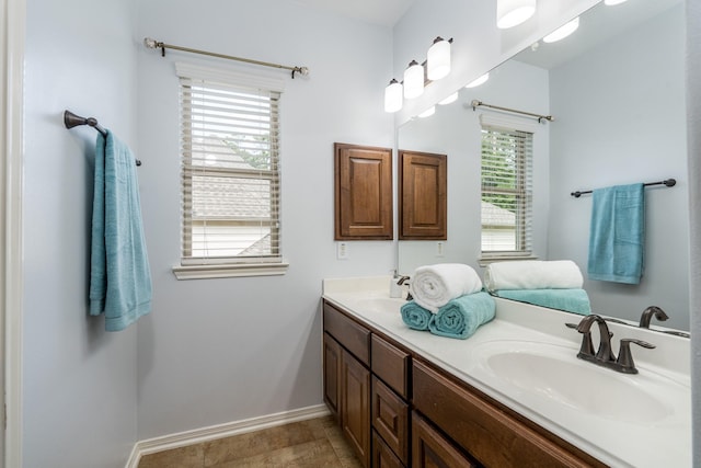 bathroom featuring double vanity, baseboards, and a sink