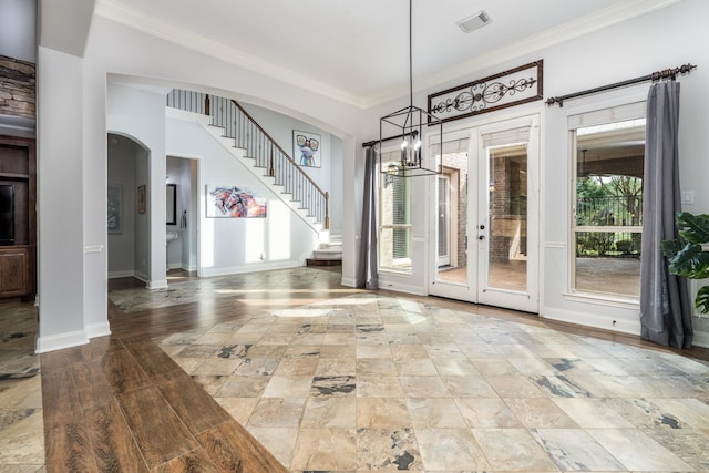 interior space featuring visible vents, arched walkways, a chandelier, ornamental molding, and stairs