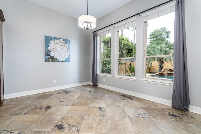 spare room with baseboards and stone tile flooring