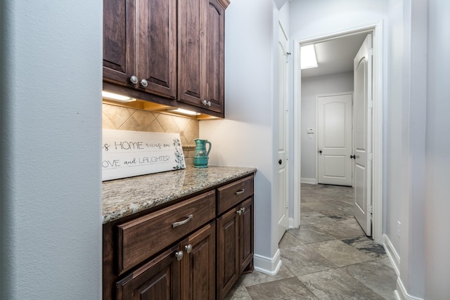 bar featuring baseboards, tasteful backsplash, and stone finish floor