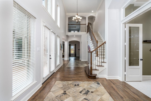 entryway with stairway, arched walkways, an inviting chandelier, and a wealth of natural light