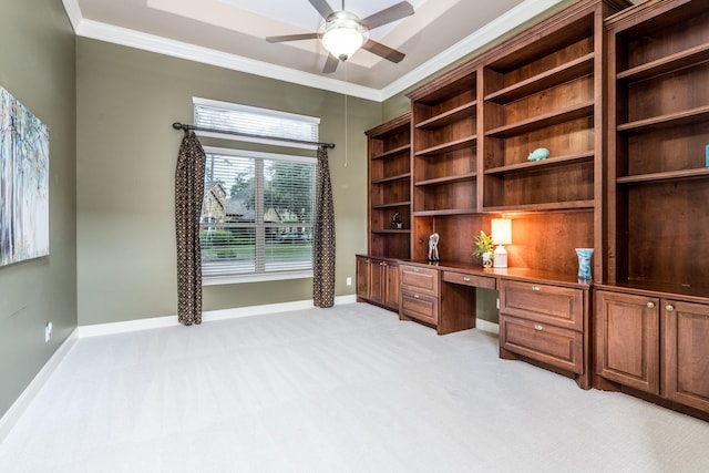 unfurnished office with ceiling fan, light carpet, built in study area, baseboards, and ornamental molding