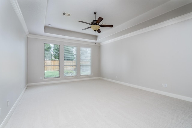 spare room with ceiling fan, visible vents, a raised ceiling, baseboards, and light carpet