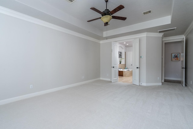 unfurnished bedroom with visible vents, baseboards, light colored carpet, and a raised ceiling