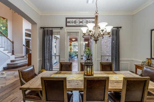 dining space with crown molding, a chandelier, french doors, wood finished floors, and stairway