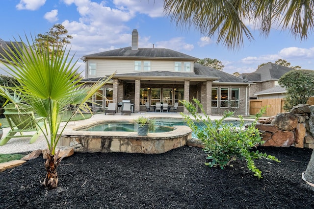 back of property featuring fence, a patio, an outdoor pool, a chimney, and brick siding