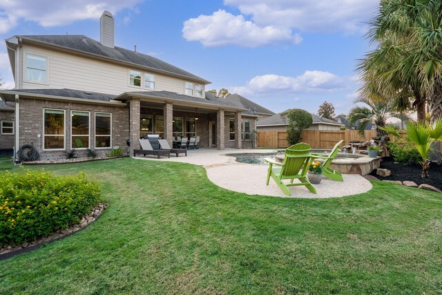 rear view of property with fence, a chimney, brick siding, a patio area, and a lawn