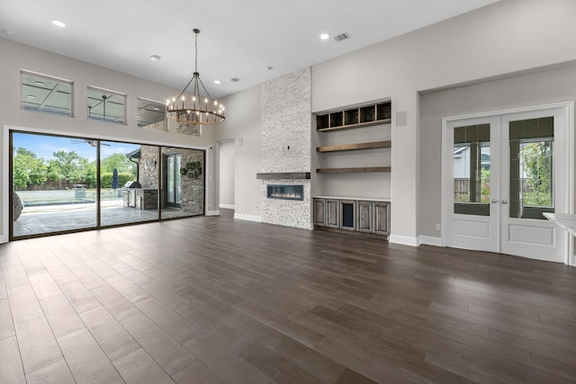 unfurnished living room with an inviting chandelier, dark wood finished floors, french doors, baseboards, and visible vents