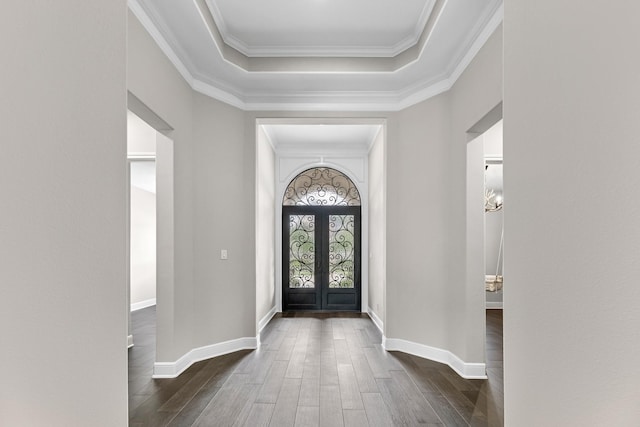 entrance foyer with ornamental molding, baseboards, dark wood-type flooring, a tray ceiling, and french doors