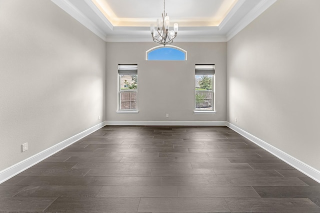 empty room featuring an inviting chandelier, crown molding, a tray ceiling, and dark wood-type flooring