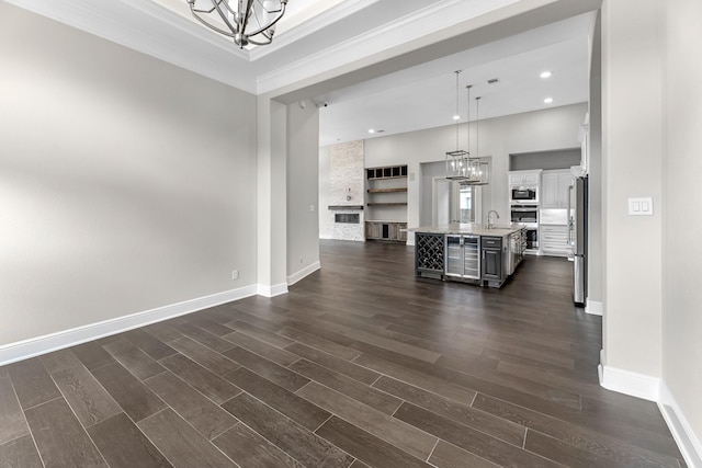 living area with dark wood-style flooring, crown molding, baseboards, an inviting chandelier, and recessed lighting