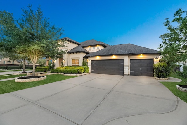 view of front of property with stucco siding, an attached garage, driveway, and a front yard