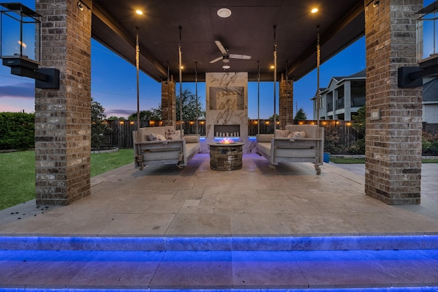 view of patio featuring ceiling fan, fence, and an outdoor living space with a fireplace