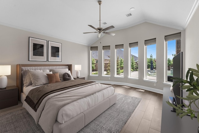 bedroom featuring visible vents, multiple windows, wood finished floors, and vaulted ceiling