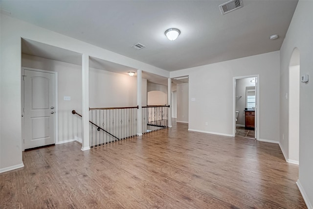 spare room featuring baseboards, wood finished floors, and visible vents