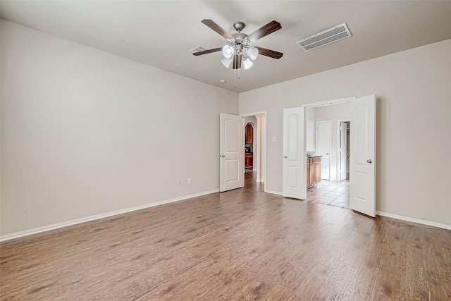 unfurnished bedroom featuring baseboards, a ceiling fan, wood finished floors, and visible vents