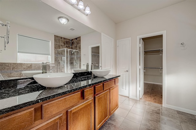 bathroom with double vanity, a sink, tile patterned flooring, and a stall shower