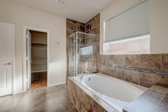 full bathroom featuring baseboards, a spacious closet, visible vents, a garden tub, and a stall shower